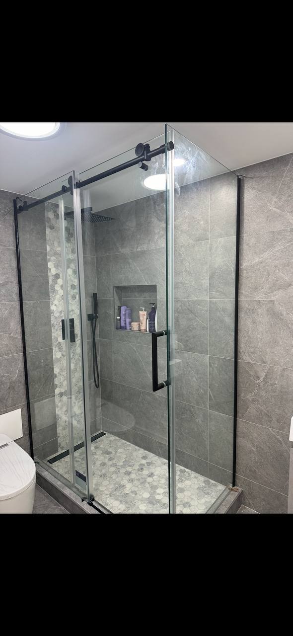 Modern glass shower with gray marble tile and matte black hardware